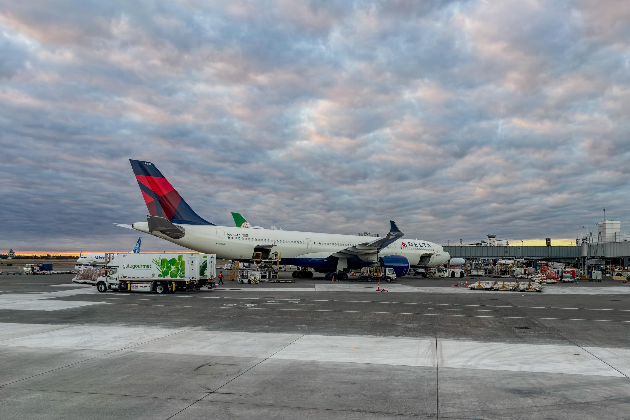 Seattle-Tacoma International Airport - June 10, 2026: A Delta Air Lines plane at a gate of Seattle-Tacoma International Airport during sunset golden hour with sky full of colorful clouds. HDR encoded