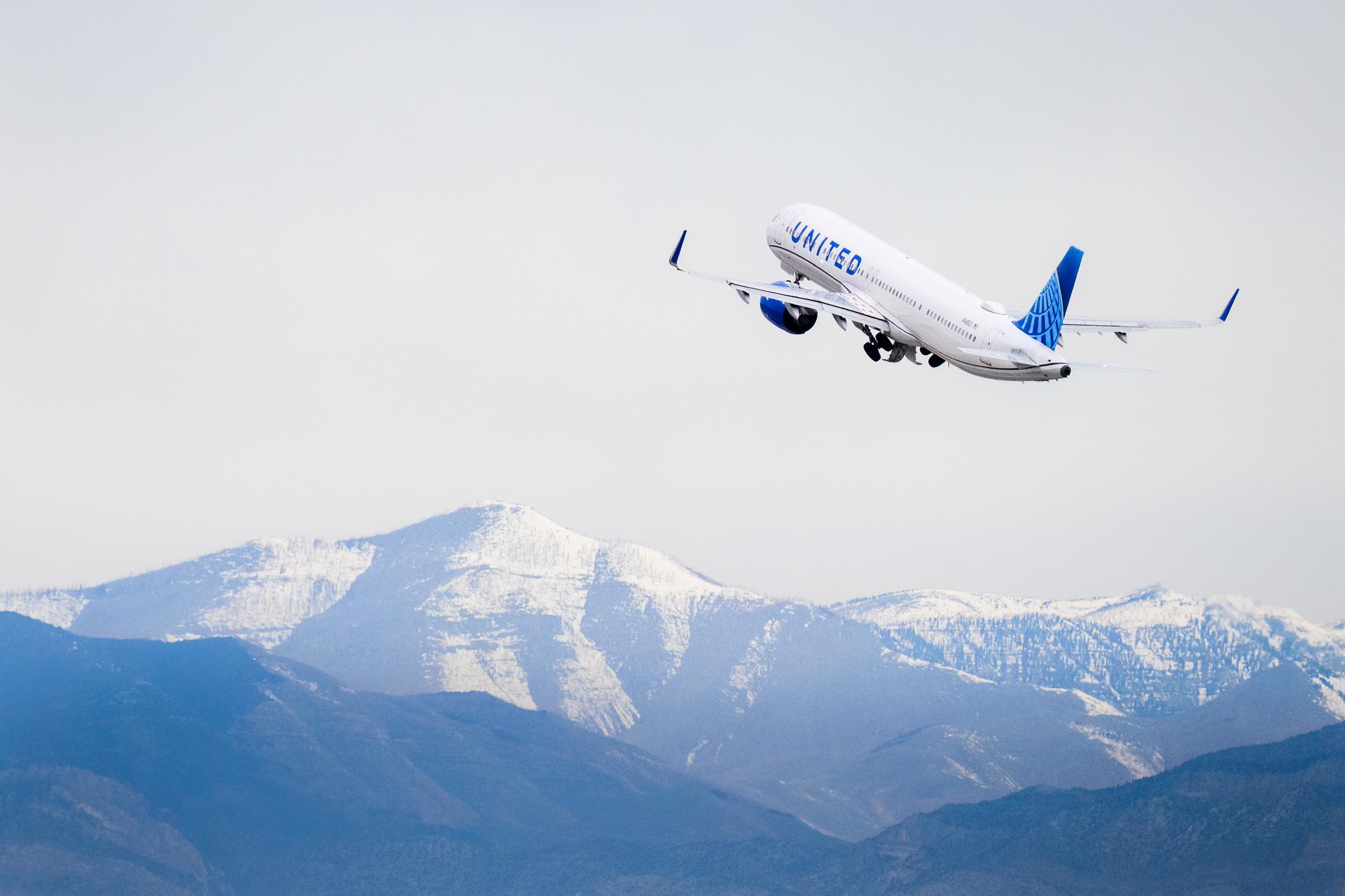 United Airlines N14502 Airbus A321-271NX taking off from Harry Reid International Airport, flying over snow-capped mountains.